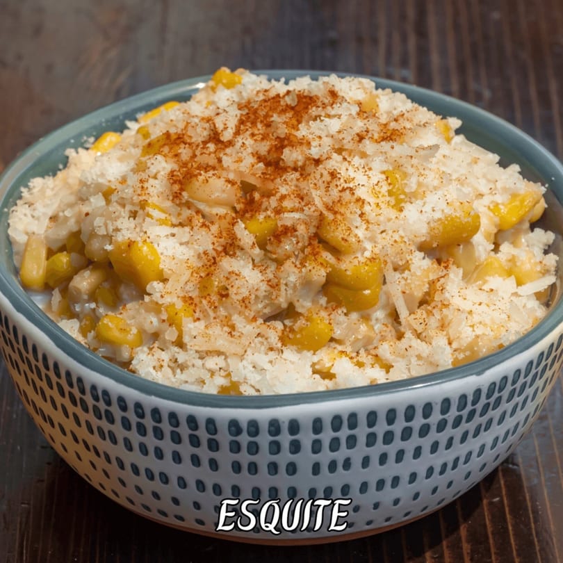 A bowl of esquite, Mexican street corn salad, topped with cheese and chili powder.