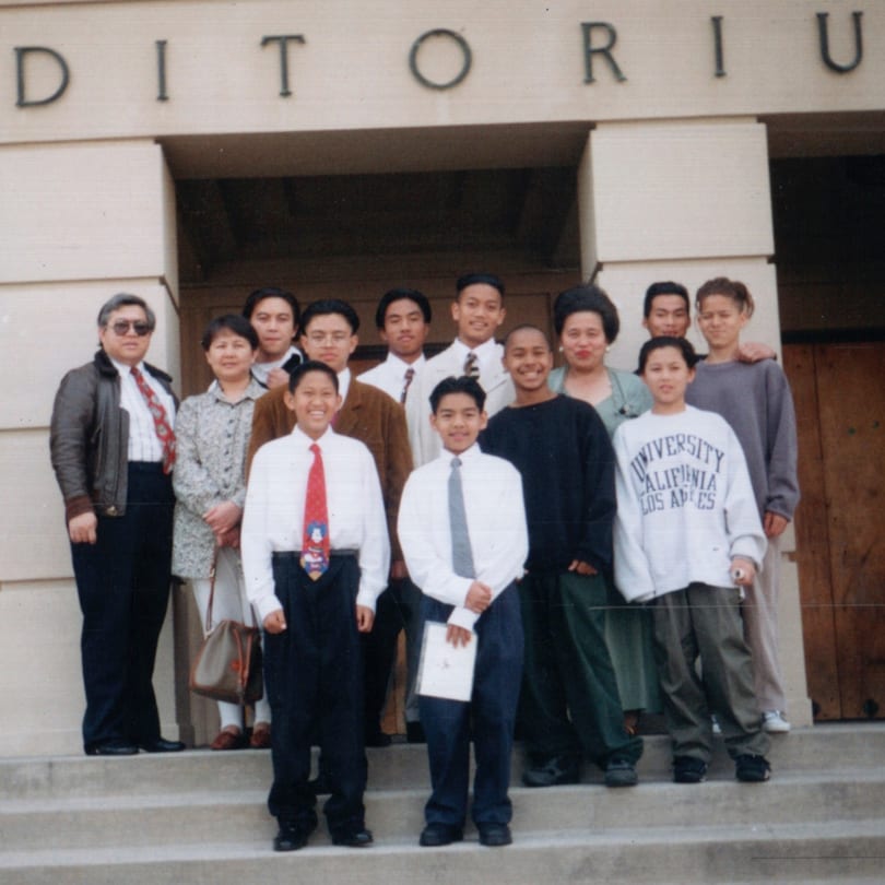 A large group of Filipino people, including adults and children, posing on steps in front of a building.