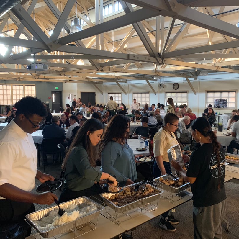 Guests at The Park's Finest buffet line serving themselves Filipino food in a large hall.