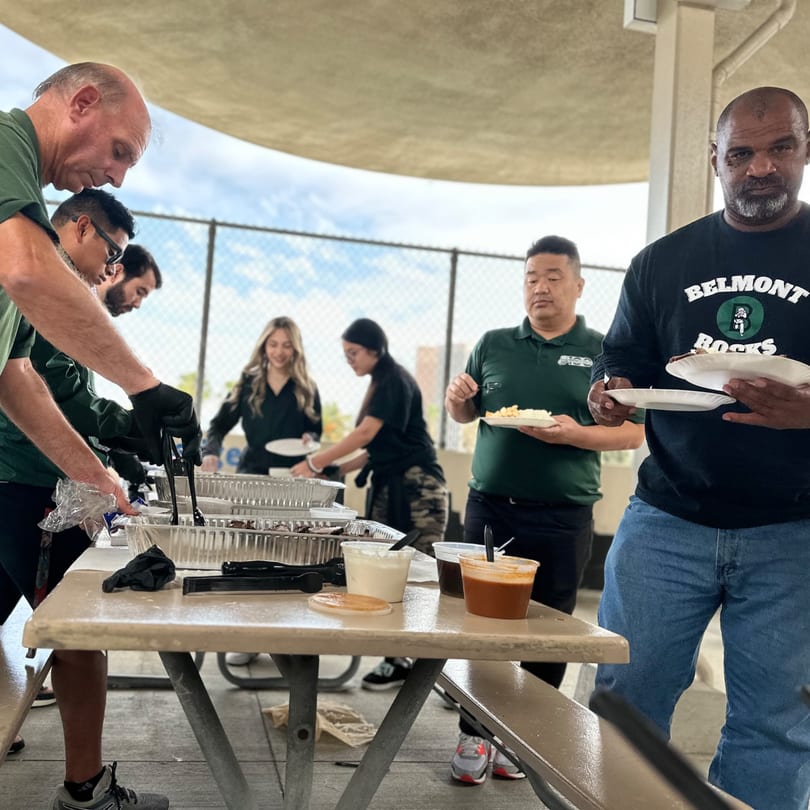 People serving and receiving Filipino food from The Park's Finest at an outdoor event.